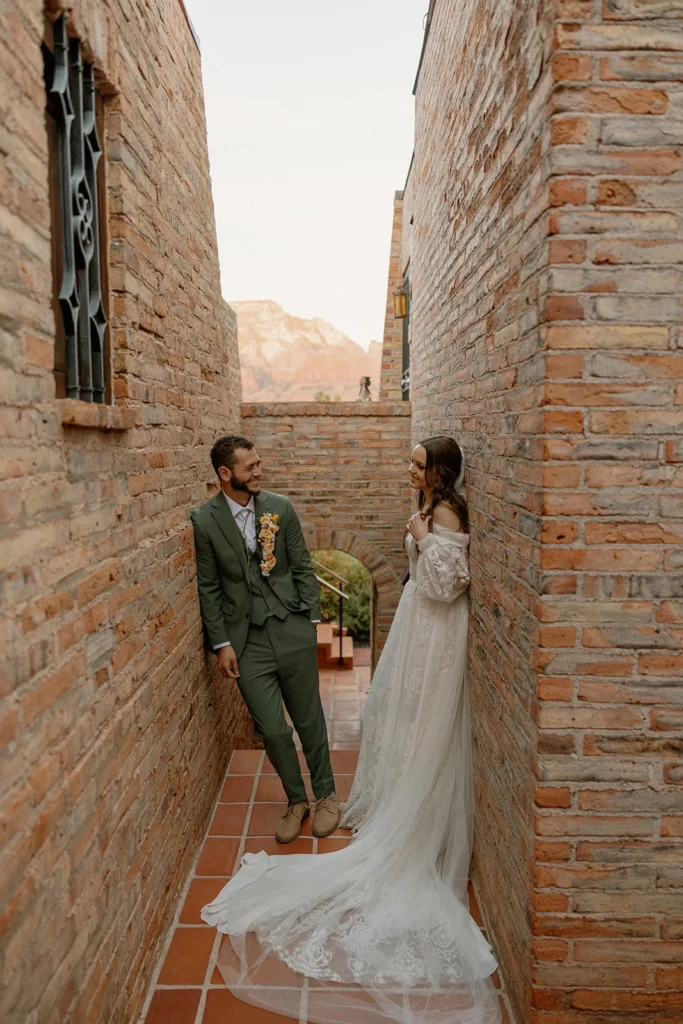 Wedding couple smiling at each other in a small corridor made of brick walls at the Eagle Dancer Resort 